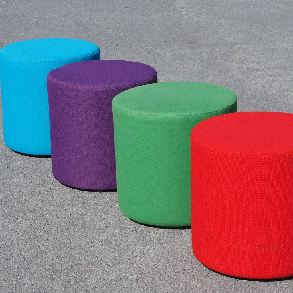 Round ottoman upholstered in various colorful fabric