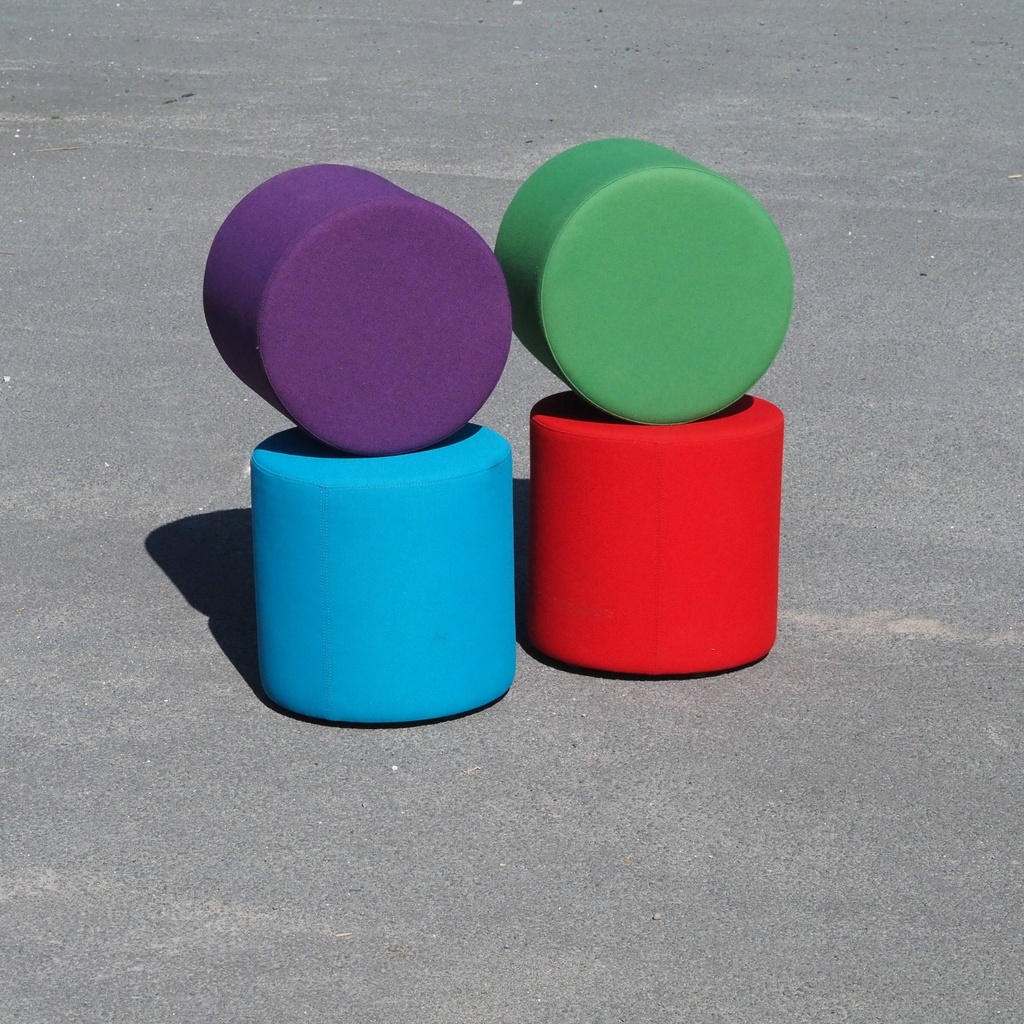 Round ottoman upholstered in various colorful fabric