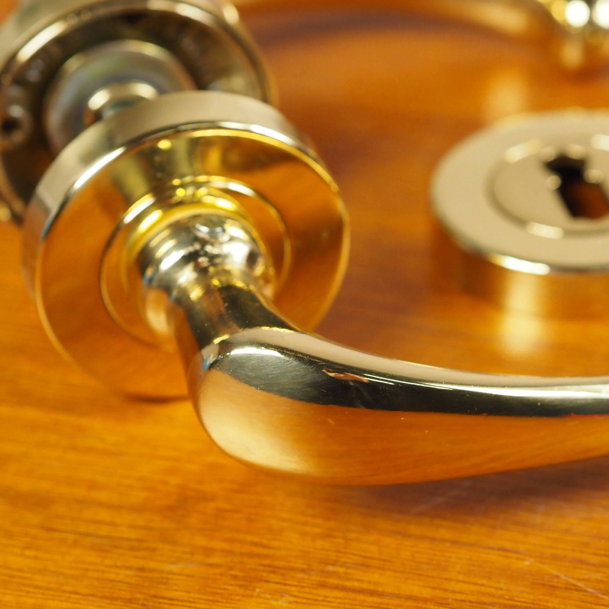 Door handle in brass plated aluminium with key rosettes by Linea Bertomani