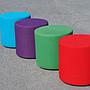 Round ottoman upholstered in various colorful fabric