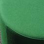 Round ottoman upholstered in various colorful fabric